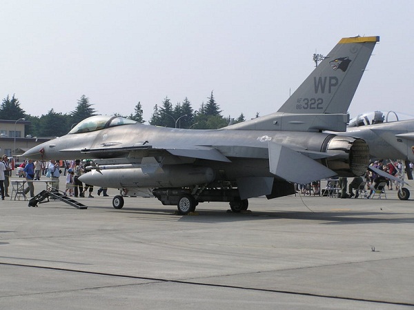  Avião de combate, F-16 Falcon, estacionado em um airshow, com estabilizadores voltados para baixo. 